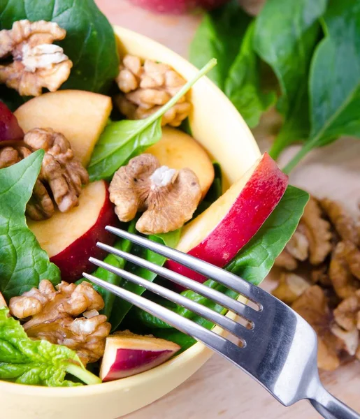 The spinach salad with nuts and apples served on table