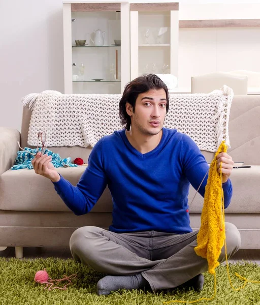 The young good looking man knitting at home
