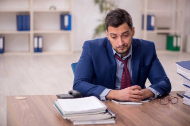 Young employee and too much work at workplace