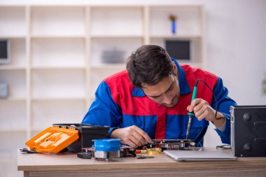 Atölyede bilgisayar tamir eden genç bir tamirci.