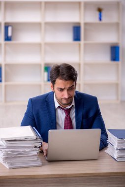 Genç işadamı ve işyerinde çok fazla iş var.