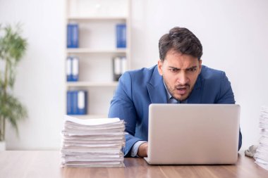 Young employee and too much work at workplace