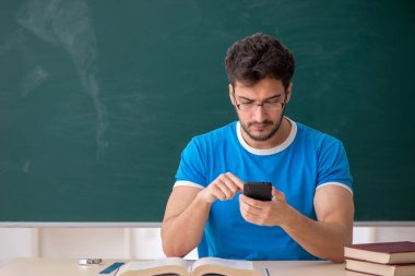 Sınıfta akıllı telefon tutan genç bir öğrenci.