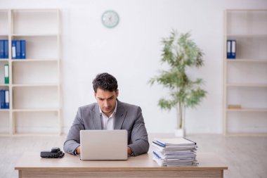 Young employee and too much work at workplace