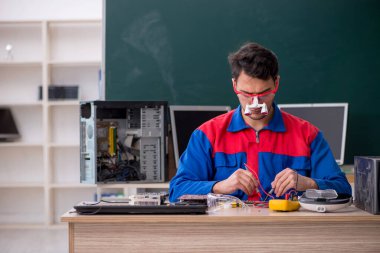 Sınıfta bilgisayar tamir eden genç bir tamirci.