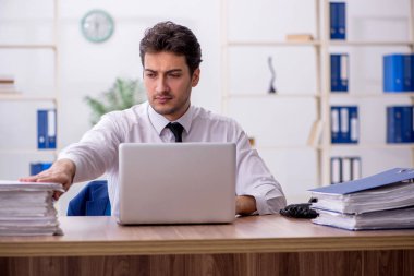 Young employee and too much work at workplace