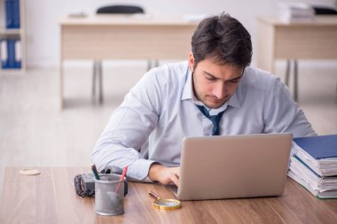 Genç erkek çalışan işyerinde oturuyor.