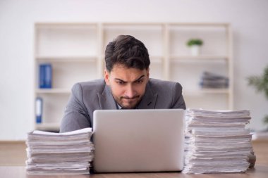 Young employee and too much work at workplace