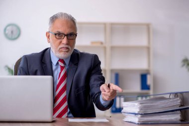 Old employee sitting at workplace