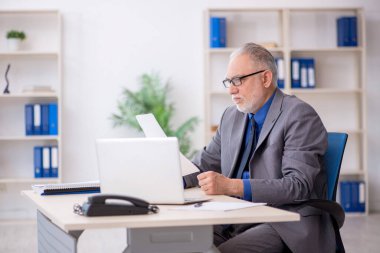 İş yerinde gazete okuyan eski bir çalışan.