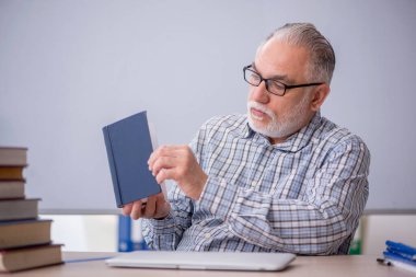 Eski öğretmen sınıfta kitap öneriyor.