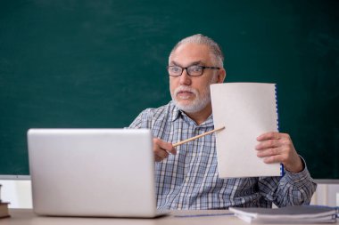 Old teacher sitting in the classroom