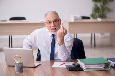 Old employee sitting at workplace