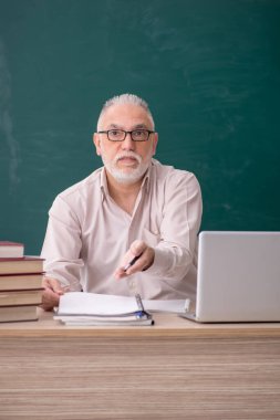 Old teacher sitting in the classroom
