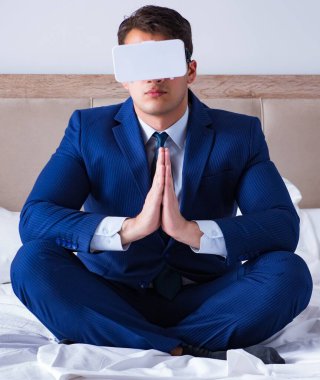 İş adamı yatak odasında sanal gerçeklik kulaklığı takıyor.