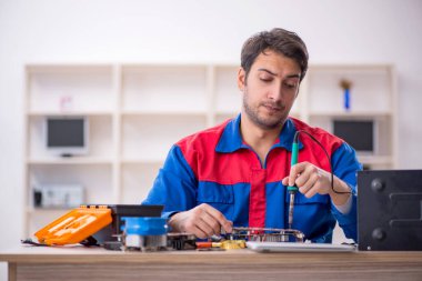 Atölyede bilgisayar tamir eden genç bir tamirci.