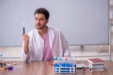 Young chemistry teacher sitting in the classroom