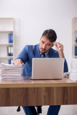 Young employee and too much work at workplace