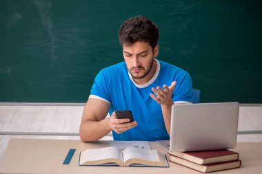 Sınıfta akıllı telefon tutan genç bir öğrenci.