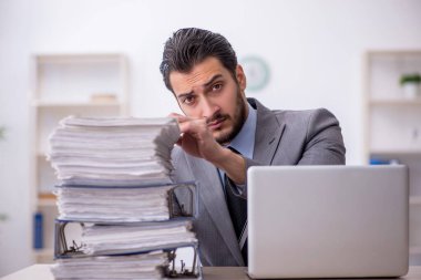 Genç bir çalışan ve ofiste çok fazla iş var.