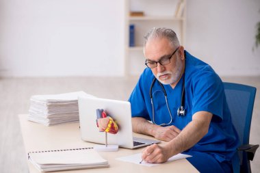 Klinikte çalışan yaşlı bir doktor.