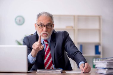 Old employee sitting at workplace