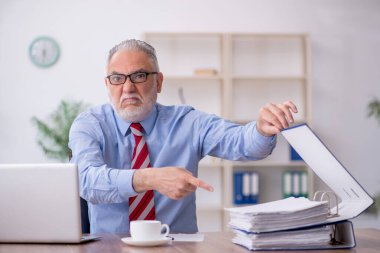 Old employee sitting at workplace