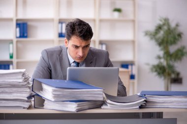 Young employee and too much work at workplace