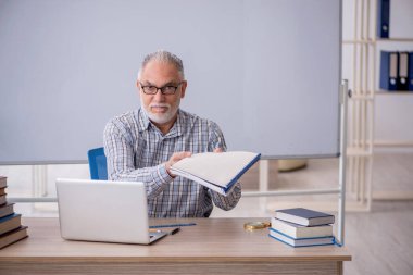 Old teacher sitting in the classroom