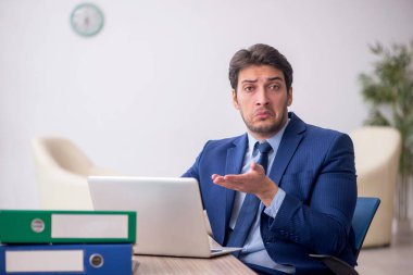 Genç işadamı işyerinde oturuyor.