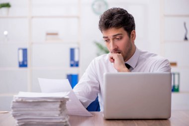 Young employee and too much work at workplace