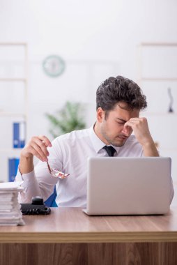 Young employee and too much work at workplace