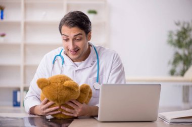Genç doktor oyuncak ayı tutuyor.
