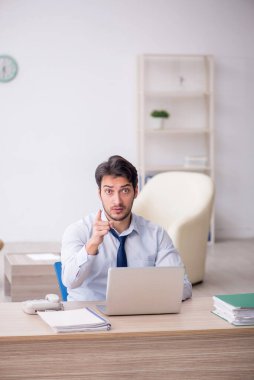 Genç işadamı işyerinde oturuyor.