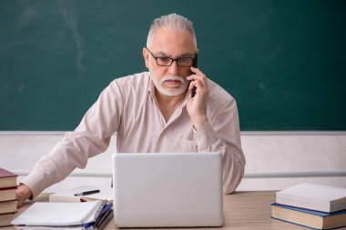 Old teacher sitting in the classroom