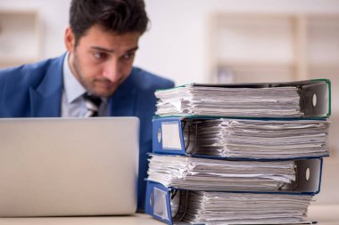 Genç işadamı ve işyerinde çok fazla iş var.