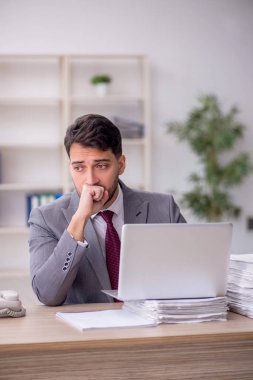 Young employee and too much work at workplace
