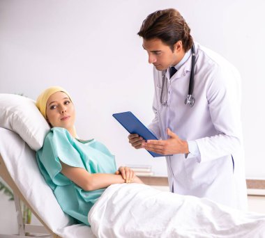Genç, yakışıklı doktor kadın onkoloji hastasını ziyaret ediyor.