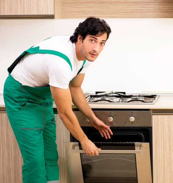 The young contractor repairing oven in kitchen