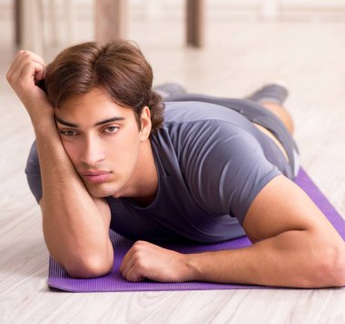 Genç yakışıklı adam evde spor egzersizleri yapıyor.