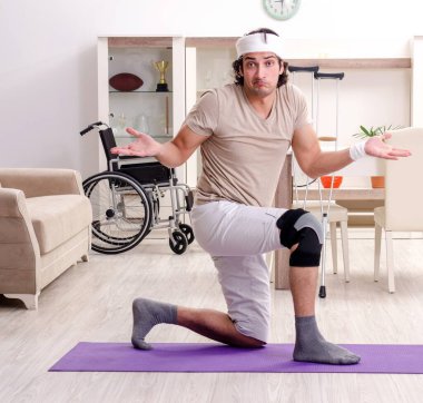 Evde egzersiz yapan yaralı genç adam.