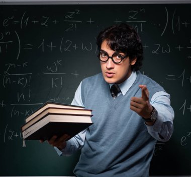 Tahtanın önündeki genç matematik öğretmeni.