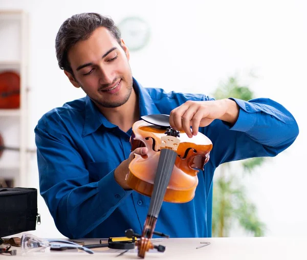 Young male repairman repairing the violin