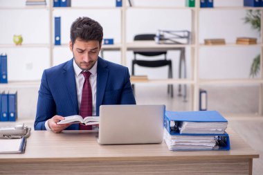 Genç işadamı ofiste kitap okuyor.
