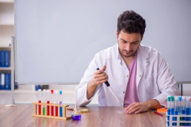 Young chemistry teacher sitting in the classroom