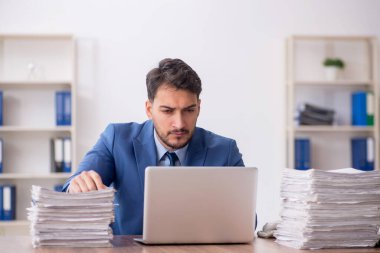 Young employee and too much work at workplace