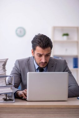 Genç bir çalışan ve ofiste çok fazla iş var.