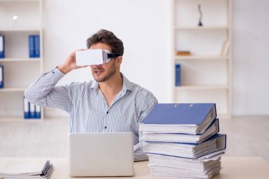 Genç çalışan ofiste sanal gözlüklerle eğleniyor.