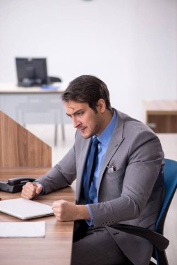 Genç işadamı işyerinde oturuyor.