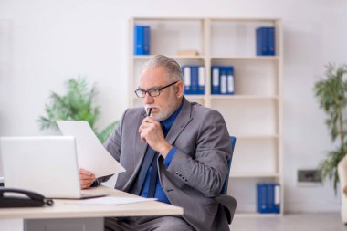 İş yerinde gazete okuyan eski bir çalışan.